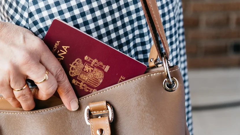 Primer plano del bolso de una persona mientra introduce su pasaporte español